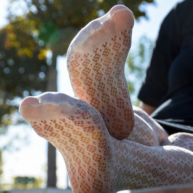 Sexy legs in white fishnet tights in the park