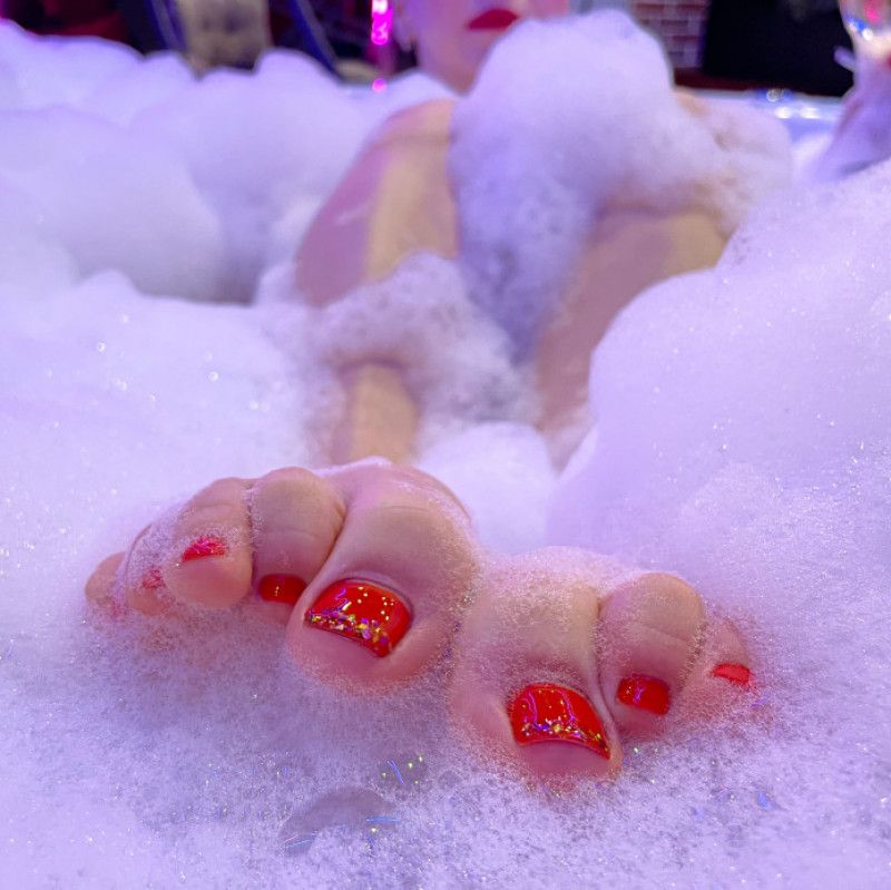 Lovely feet and toes with red toenails in a bubble bath