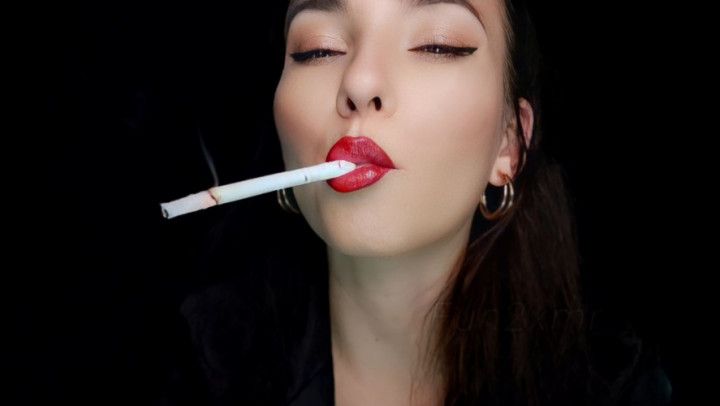 A closeup shot of smoking a white  cigarette with red lips