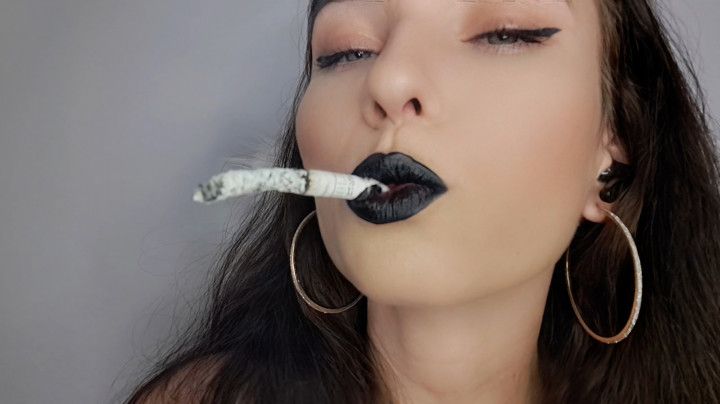 Sultry brunette with black lips smokes up close to you