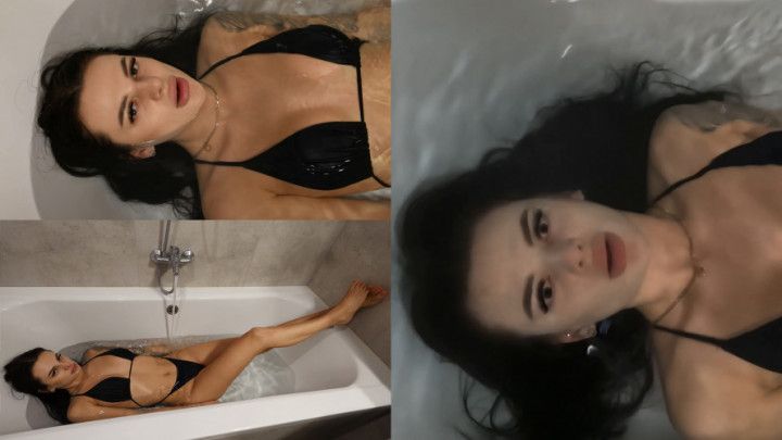 Jade lies in the filling bathtub and goes under the water