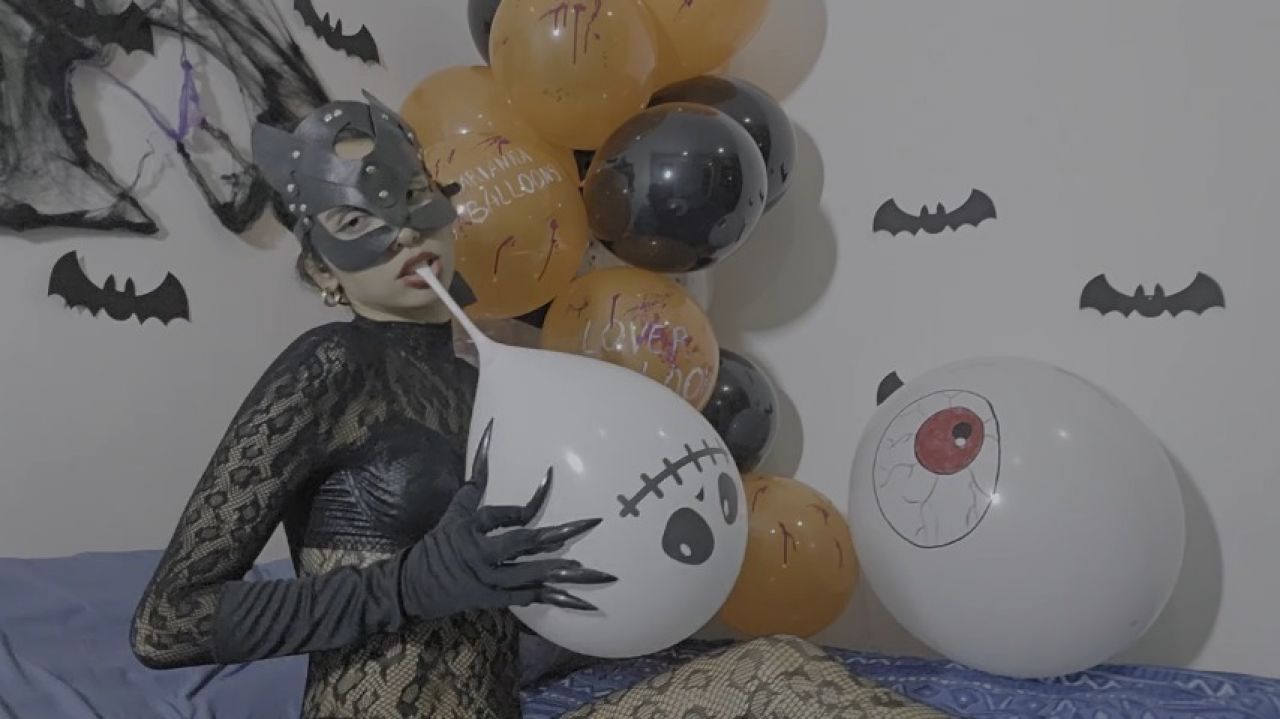 Catwoman on Halloween bursts balloons with her claws