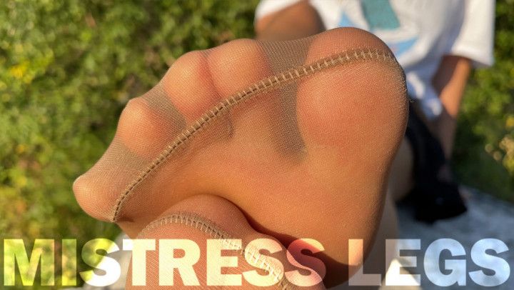 Mistress in tan tights teases you with her cute feet outdoor