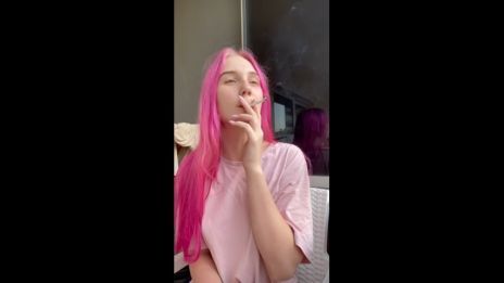 a young pink-haired girl smokes and enjoys the view outside