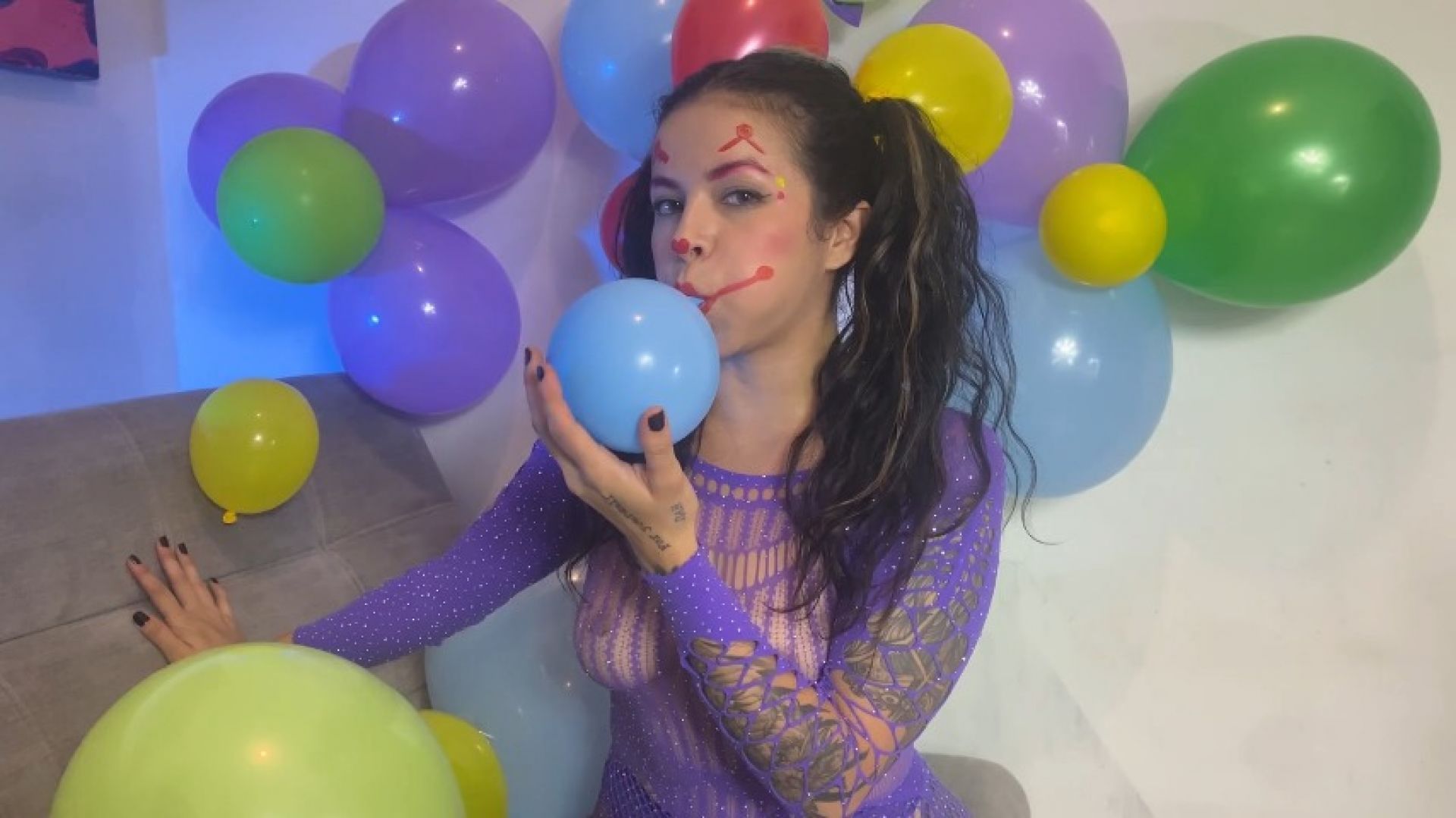 Beautiful clown has fun inflating balloons