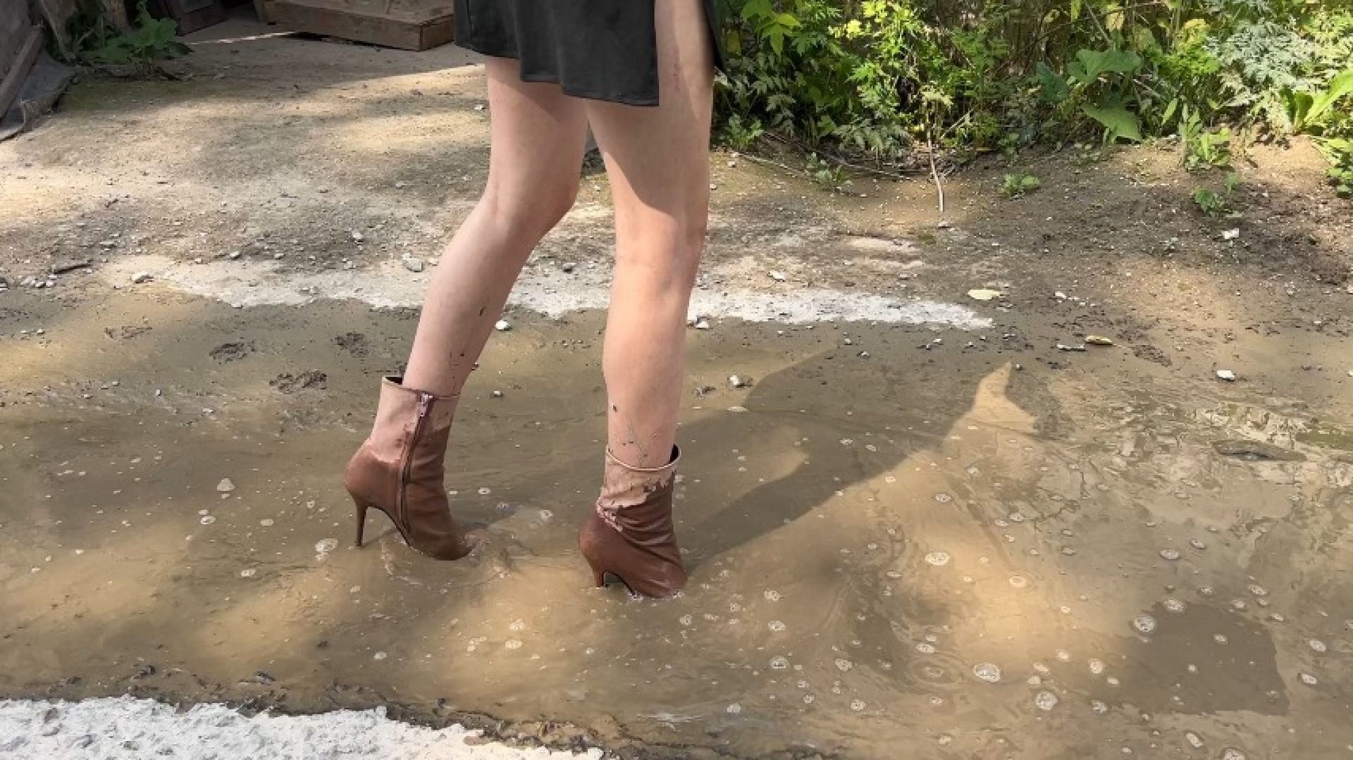 girl in high-heeled boots walks through muddy puddles