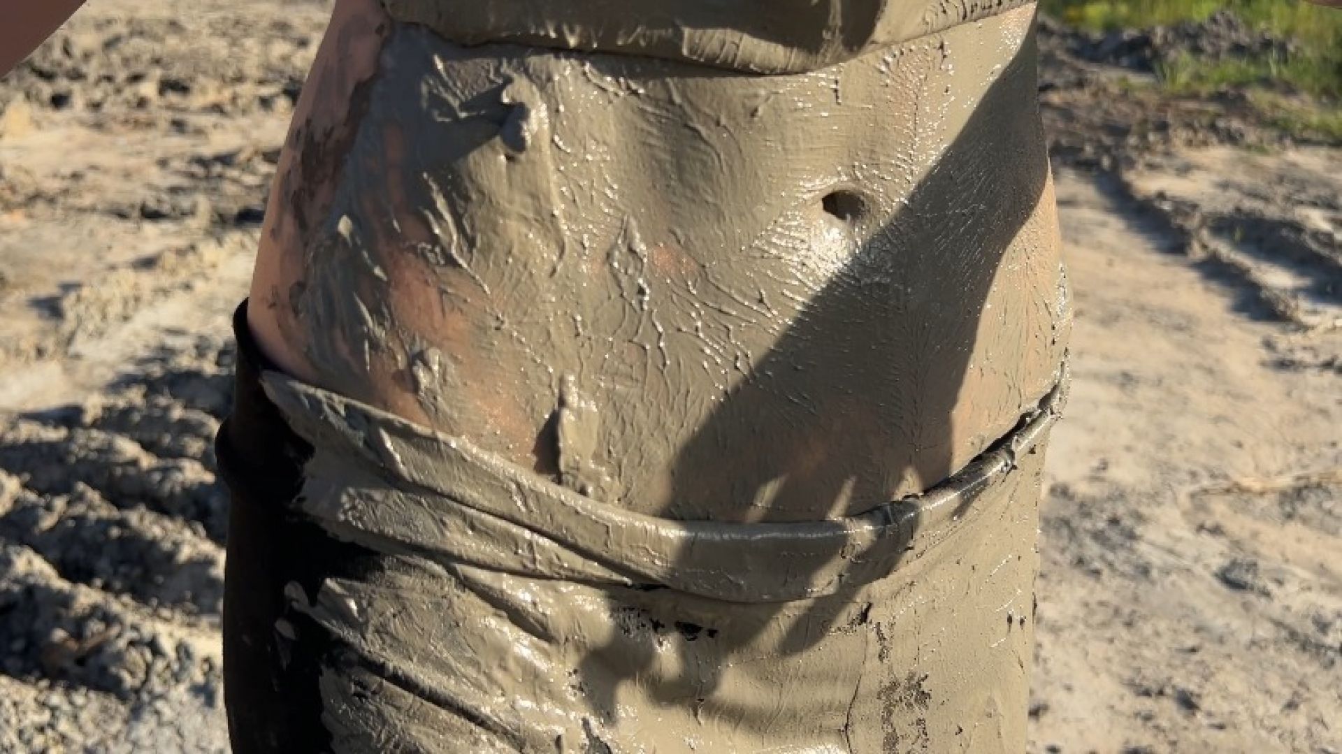 girl stains her stomach with mud by lying in it several time