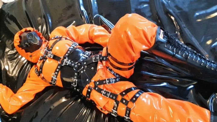 Orange latex rainwear, corset and harness, jerking off a guy