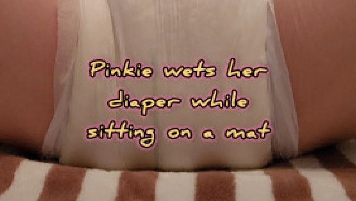 Pinkie wets her diaper while sitting on a mat