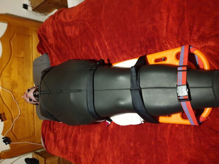 Miss M has a man strapped down in neoprene bondage sack