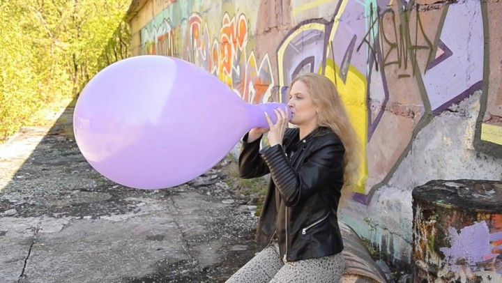 Katya Blows To Pop Purple Balloon