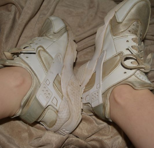 Very worn white Nike running shoes