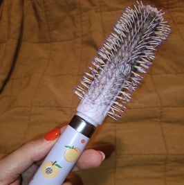 Peach handle blow dry brush with hair in