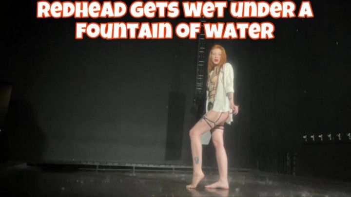 redhead gets wet under a fountain of water